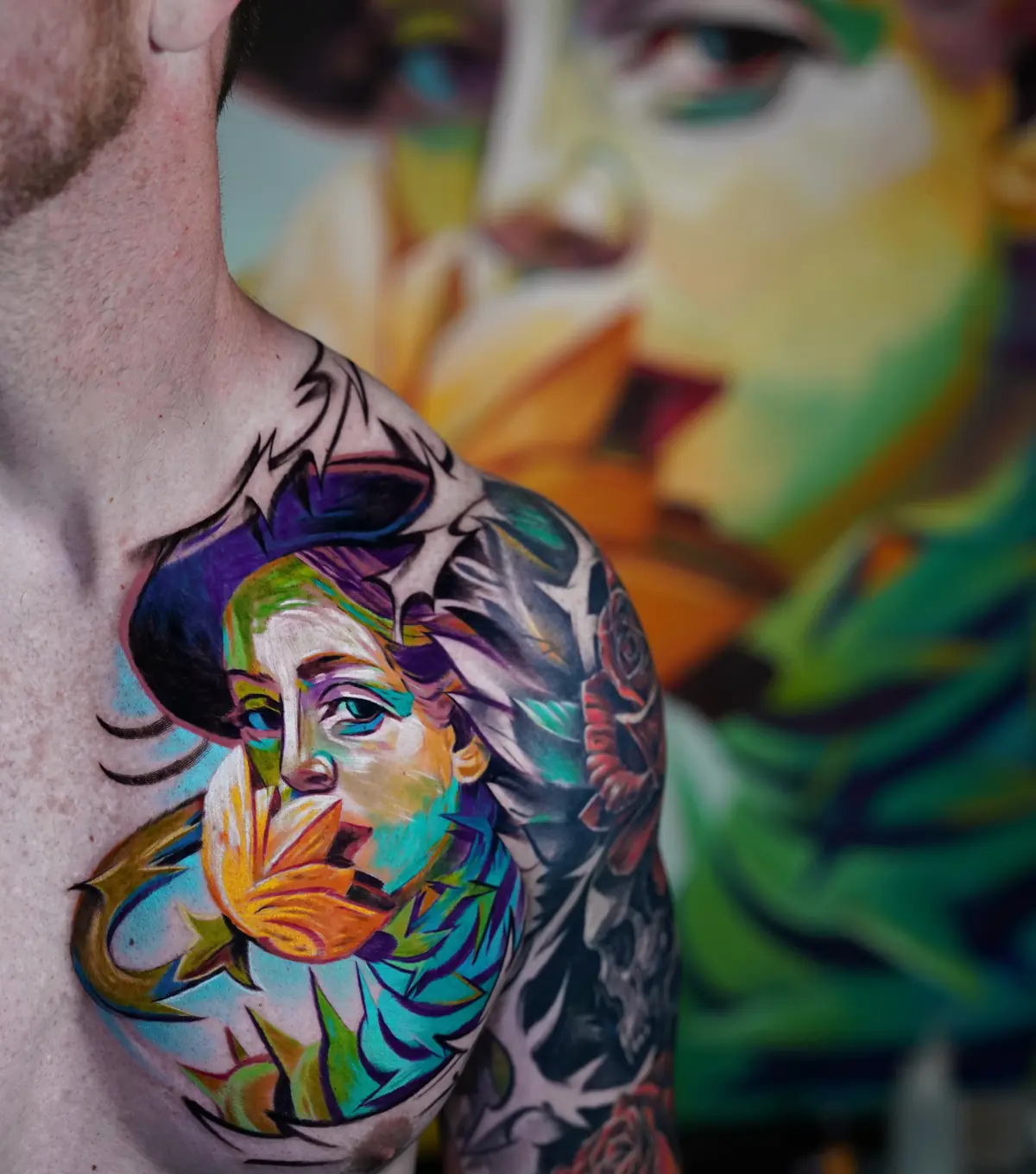 Abstract color portrait tattoo across the chest and shoulder with teal, orange, purple, and green details