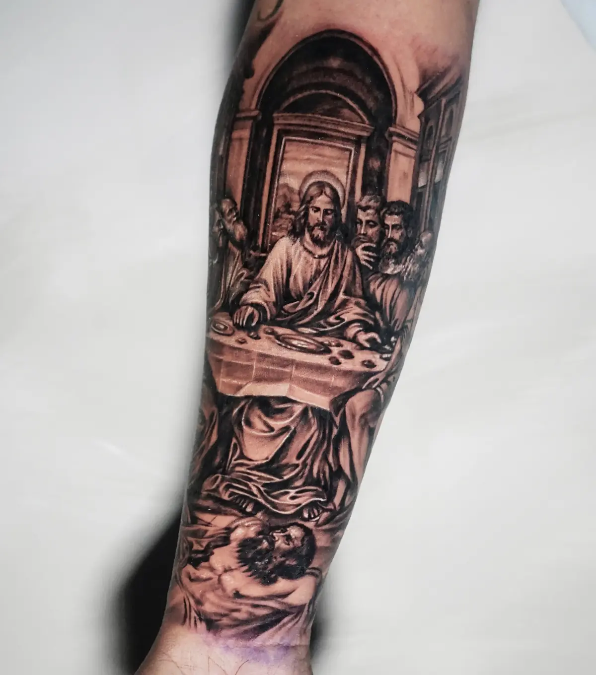 Detailed black and grey Last Supper tattoo arranged vertically along the forearm