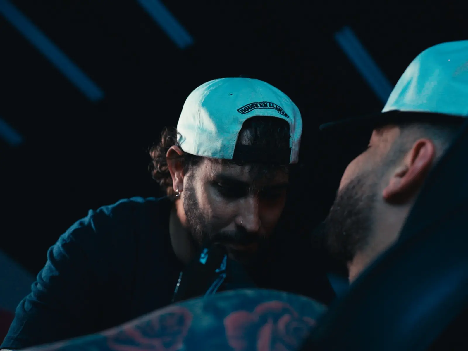 Tattoo artist working closely on a custom tattoo inside House en Llamas