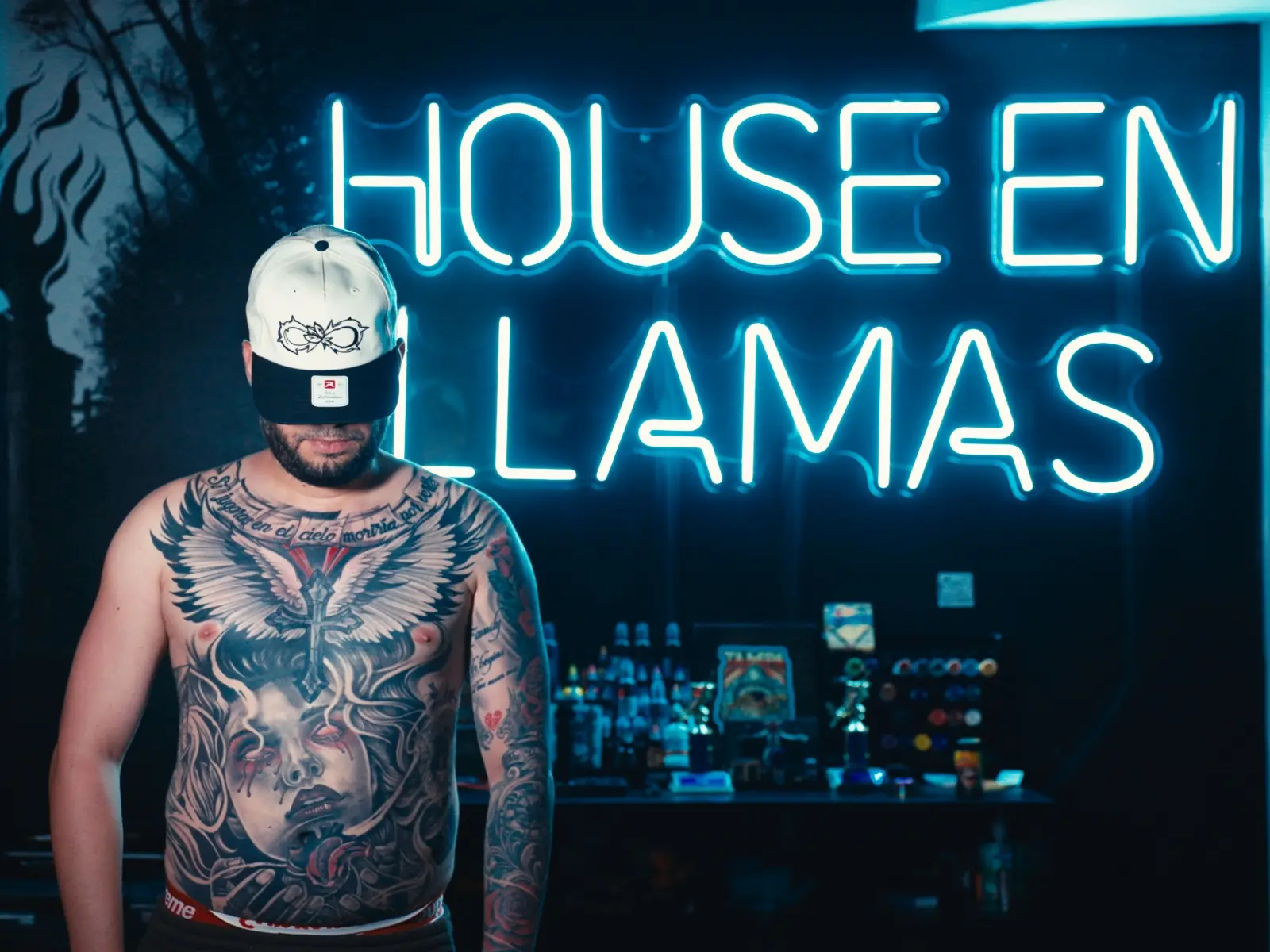 Completed chest tattoo displayed beneath the House en Llamas neon sign