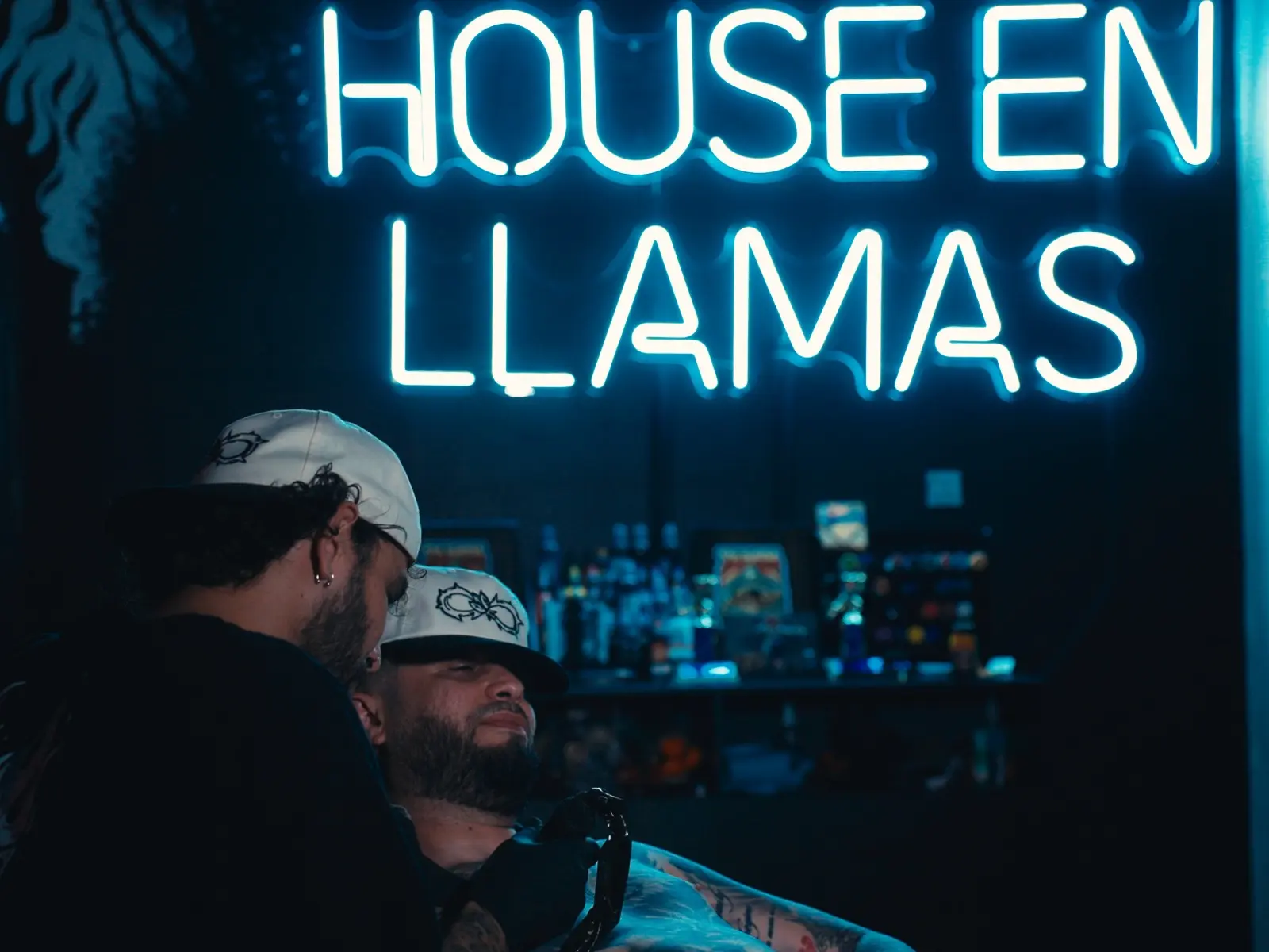 Tattoo session beneath the House en Llamas neon sign